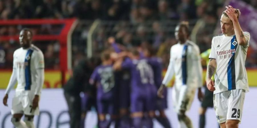 Während im Hintergrund die Osnabrücker Spieler feiern lassen die Hamburger die Köpfe hängen. Foto: Friso Gentsch/dpa