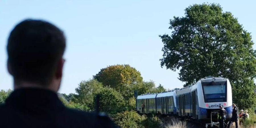 Ein Polizist steht in der Nähe des Unglücksortes auf dem Bahngleis bei Isenbüttel. Foto: Peter Steffen