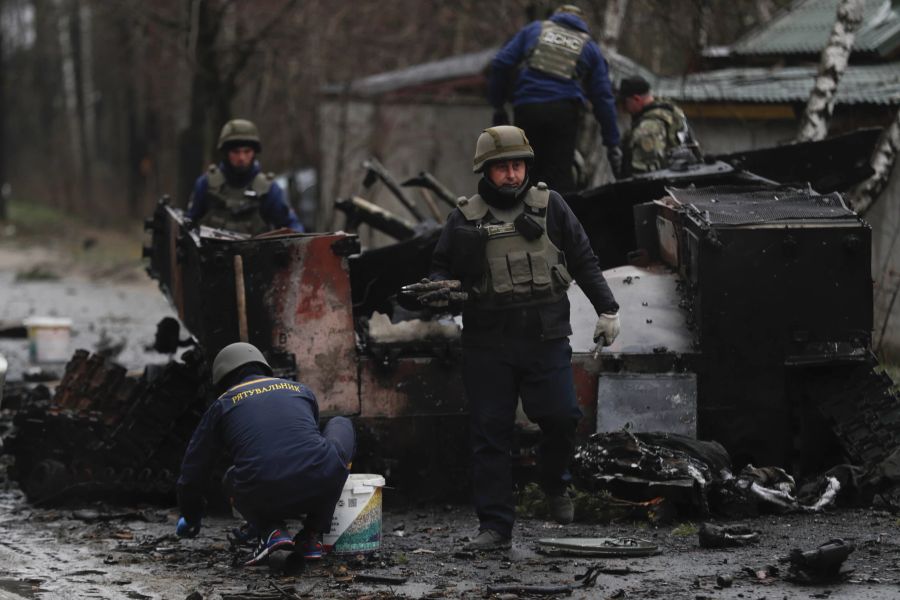 Ukrainische Soldaten tragen Munition aus einem verbrannten russischen Panzer in der Nähe der Stadt Irpin, nahe Kiew.