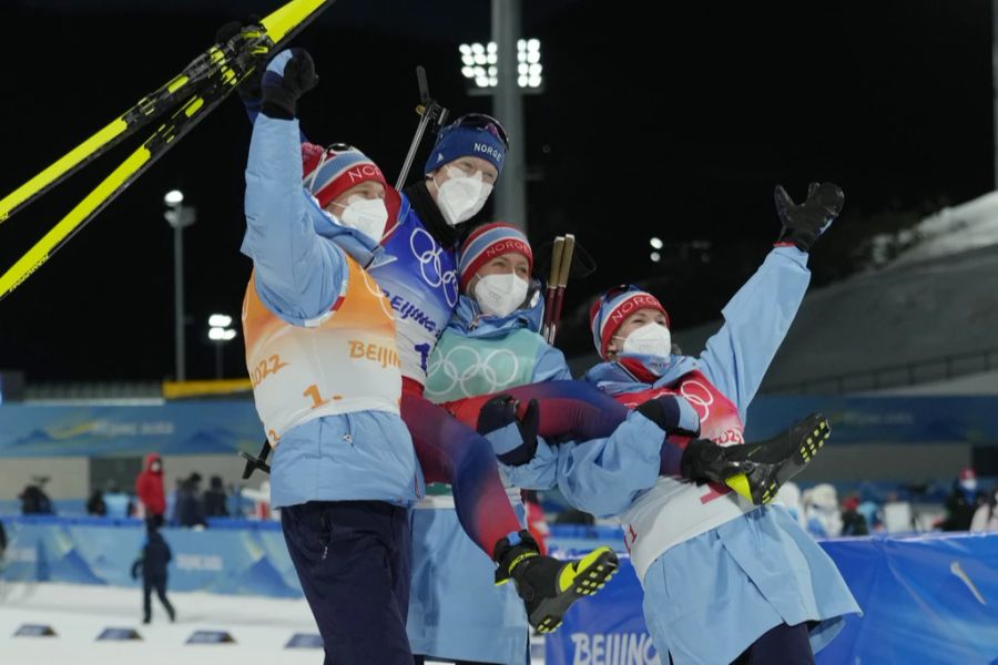 Johannes Thingnes Bö jubelt maskentragend mit seinen Biathlon-Teamkollegen.