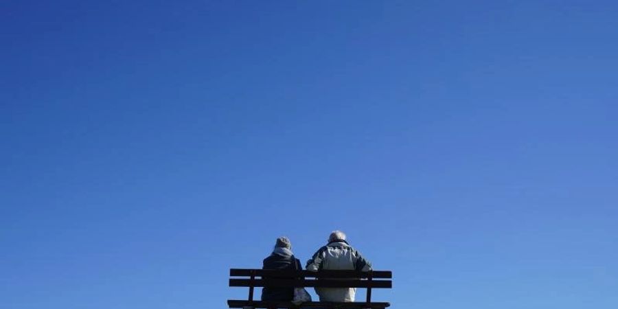 Ein älteres Paar bei strahlend blauem Himmel und Sonnenschein auf einer Bank an der Kieler Förde. Foto: Marcus Brandt/dpa