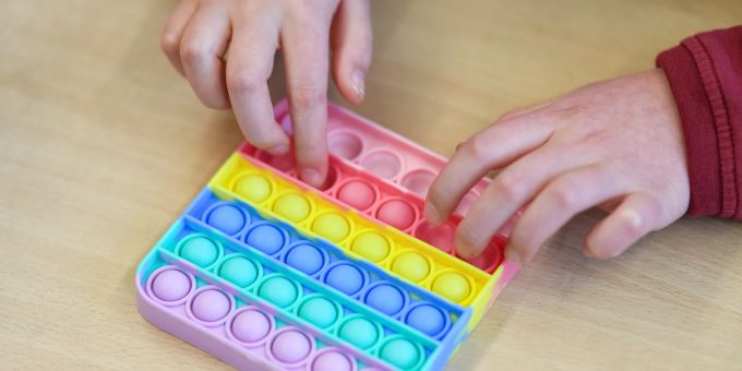 Ein Pop-it-Fidget-Toy sollte nicht in der Küche eingesetzt werden, wenn es nicht ausdrücklich mit dem Aufdruck «Für Lebensmittelkontakt» gekennzeichnet ist. Kind Hände Pop-it-Toy bunt