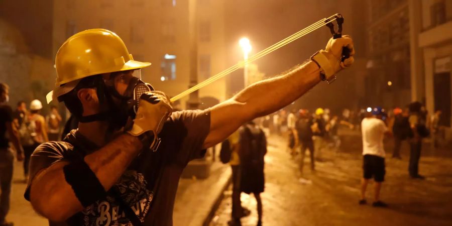 Ein Protestierender schleudert mit einer Schleuder gegen die libanesische Bereitschaftspolizei, während eines regierungskritischen Protests.