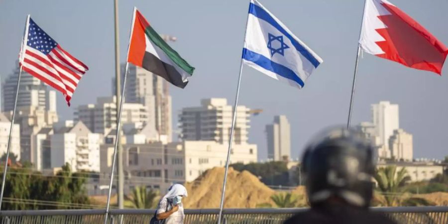 Eine Frau geht an den Flaggen der USA (l-r), der Vereinigten Arabischen Emirate, Israels und Bahrains vorbei. Foto: Ariel Schalit/AP/dpa