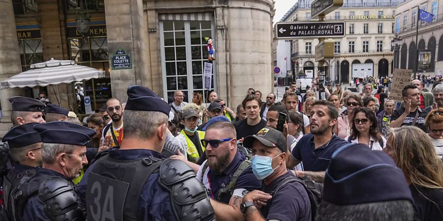 Demonstranten stehen bei einem Protest gegen den neuen Gesundheitspass in Paris Polizisten gegenüber. Foto: Michel Euler/AP/dpa