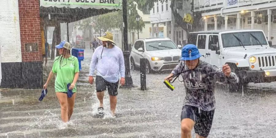 Fussgänger waten durch das Hochwasser in Key West in Florida. Foto: Rob O'neal/The Key West Citizen/AP/dpa