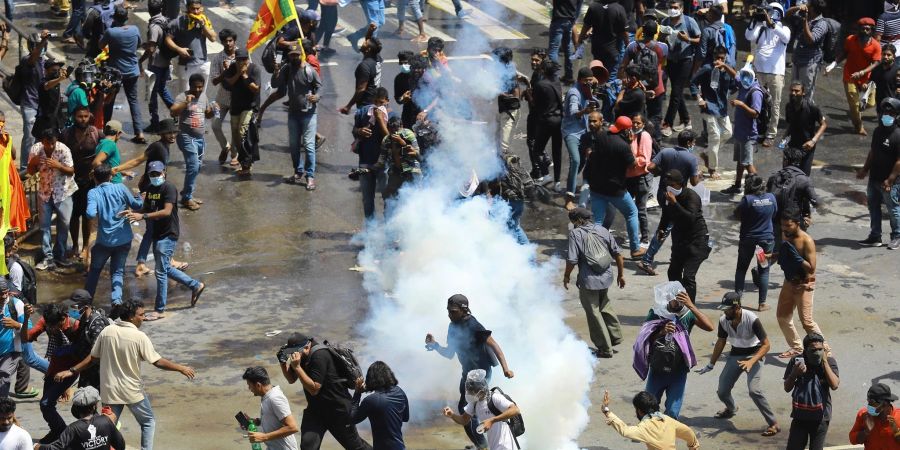 Demonstrierende fliehen vor einer von der Polizei abgefeuerten Tränengasgranate.