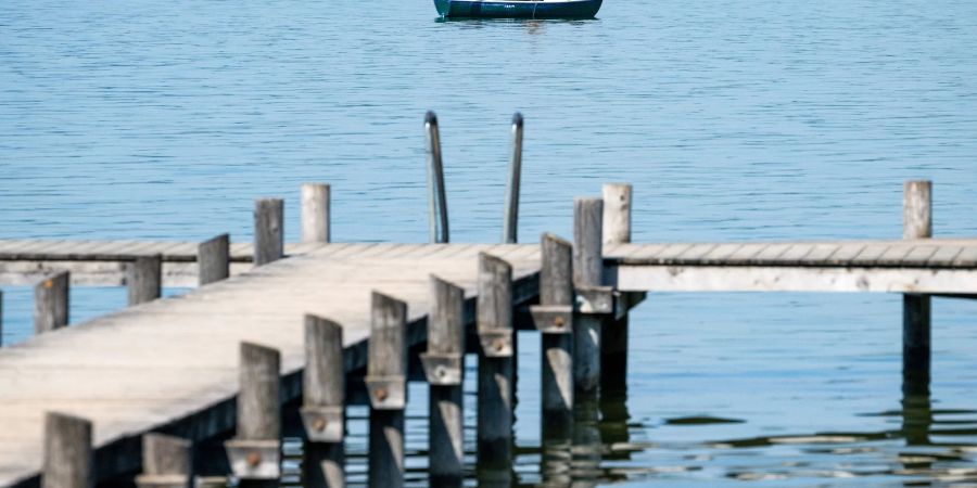 Ein Mann auf seinem Ruderboot angelt auf dem Ammersee in der Bucht von Herrsching. Mitte der Woche könnten es in manchen Orten Bayerns an die 30 Grad warm werden.