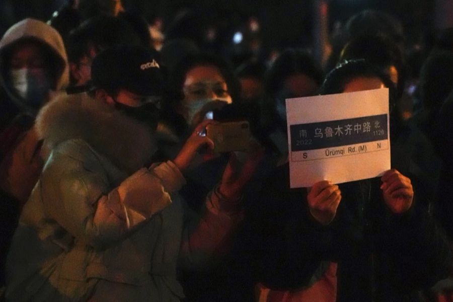 Auf dem Blatt dieser Demonstrantin ist das Strassenschild der Urumtschi-Strasse in Peking zu sehen. In Urumtschi in der Provinz Xinjiang sind zehn Menschen in einem Brand verstorben.