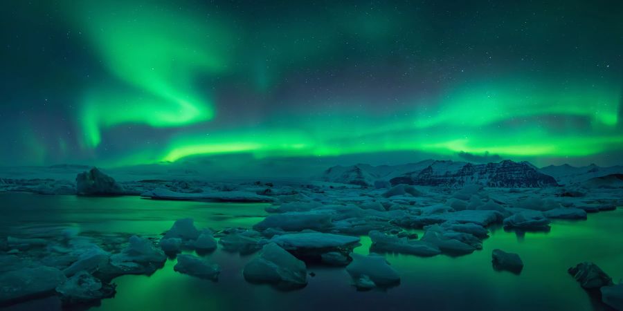 Grüne Polarlichter über einen flachen vereisten Gletscherlandschaft.
