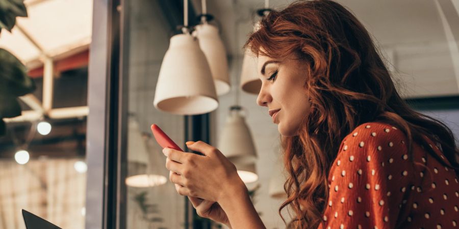 frau schaut auf smartphone, café