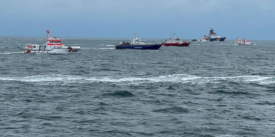 Rettungskräfte sind mit mehreren Schiffen, Tauchern und Hubschraubern im Einsatz, um nach den Schiffbrüchigen zu suchen.