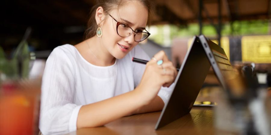 Frau 2-in-1 Laptop aufgeklappt Stift