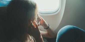 Mädchen hält sich im Flugzeug beide Ihren zu.