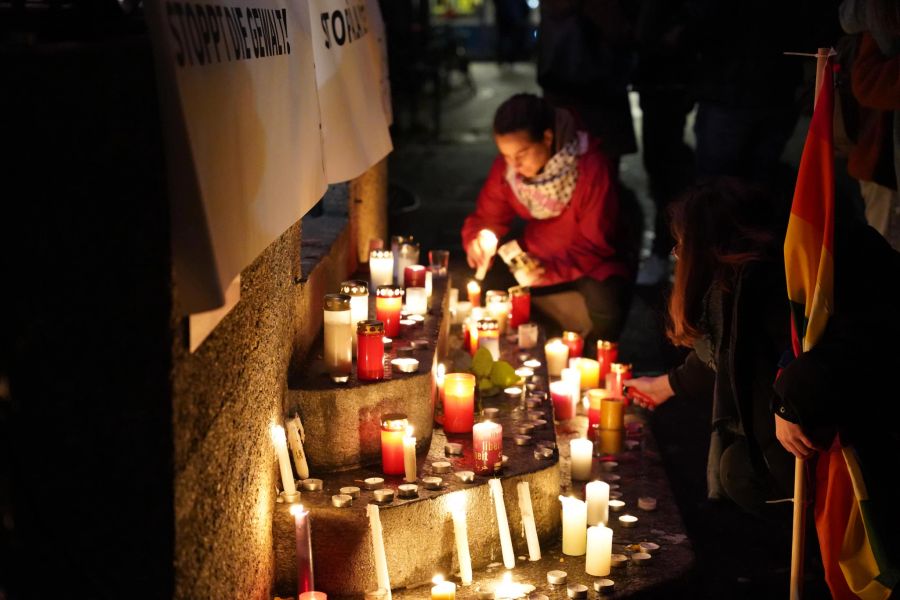 Menschen zünden auf dem Zürcher Bürkliplatz Kerzen an.