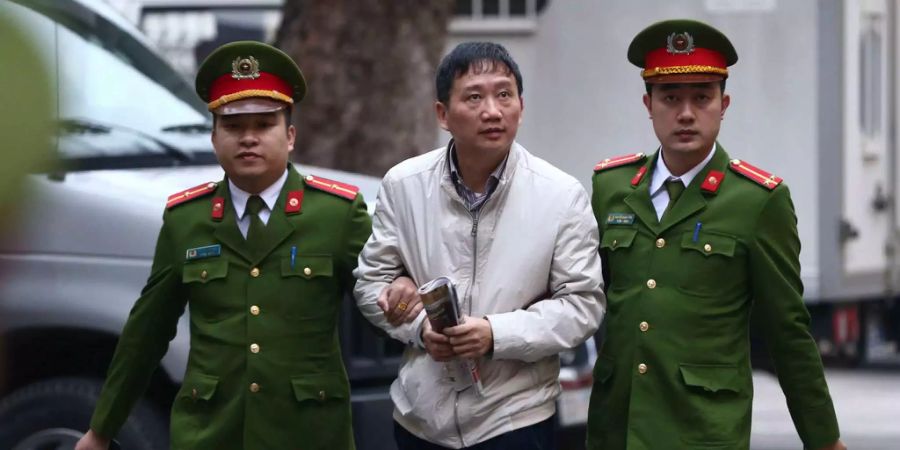 Trinh Xuan Thanh wird von zwei Polizisten zum Gerichtssaal geführt.