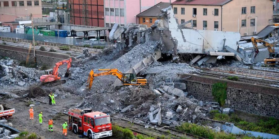 Genueser Feuerwehrleute entfernen Trümmer der teilweise eingestürzten Morandi-Autobahnbrücke.