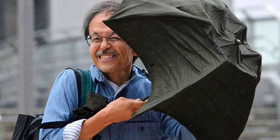 Ein Mann versucht sich mit einem Schirm gegen Wind und Regen zu schützen. Der Taifun «Shanshan» hat die Ostküste Japans mit Regenfällen überzogen.