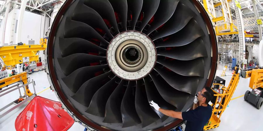 Ein neuartiges Flugzeugtriebwerk vom Typ Rolls-Royce Trent XWB wird von einem Arbeiter in einer Montagehalle begutachtet.