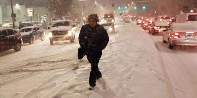 Passanten sind bei Schneefall in New York unterwegs.