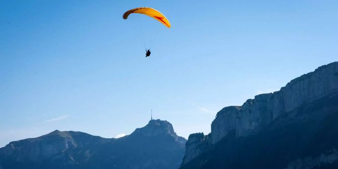 Ein Gleitschirm fliegt ueber die Ebenalp im Kanton Appenzell Innerrhoden im Hintergrund der Säntis.