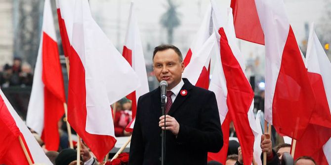 Polens Präsident Andrzej Duda bei einer Ansprache vor einer Menschenmenge mit polnischen Fahnen.