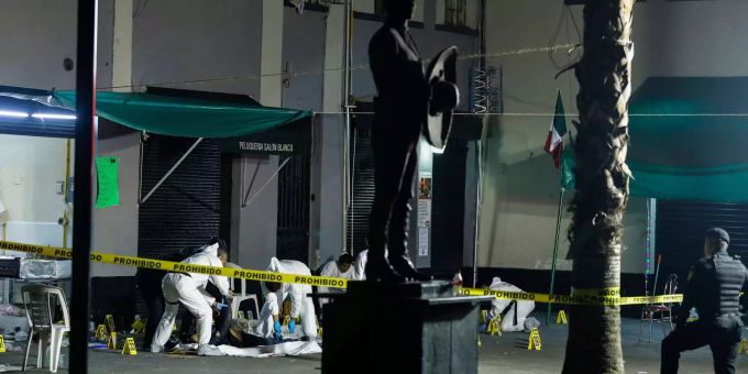 Mexikanische Polizeibeamte der Spurensicherung decken die Leichen der Opfer einer Schiesserei mit einer Folie ab. Mexikanische Polizeibeamte der Spurensicherung decken die Leichen der Opfer einer Schiesserei mit einer Folie ab.