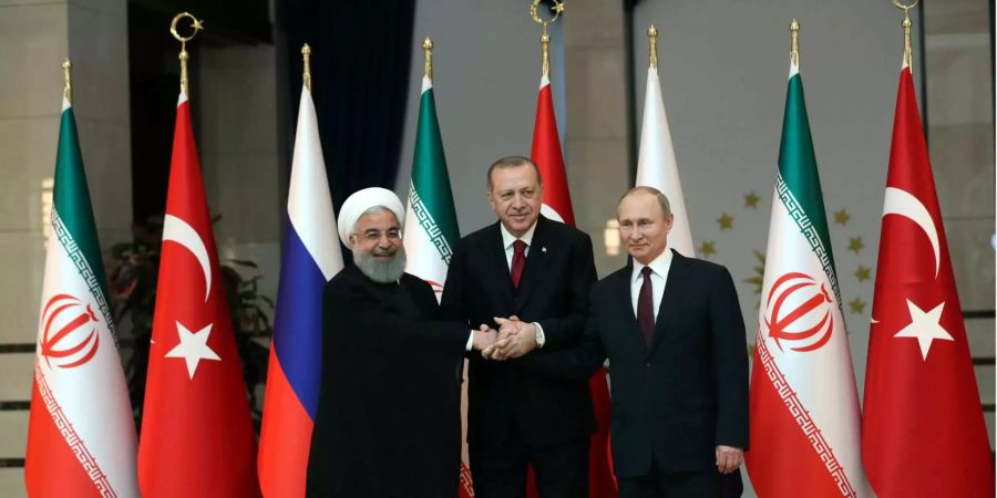 Der iranische Präsident Hassan Rouhani (l), der russische Präsident Vladimir Putin (r), und der türkische Präsident Recep Tayyip Erdogan halten sich an den Händen nach einer gemeinsamen Pressekonferenz.