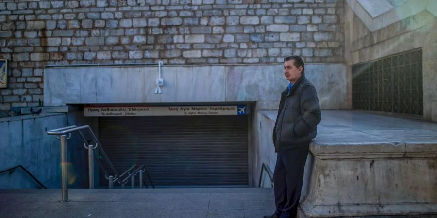 Ein Mann sitzt während eines 24-Stunden-Streiks in Griechenland vor dem geschlossenen Eingang zur Metro in Athen.