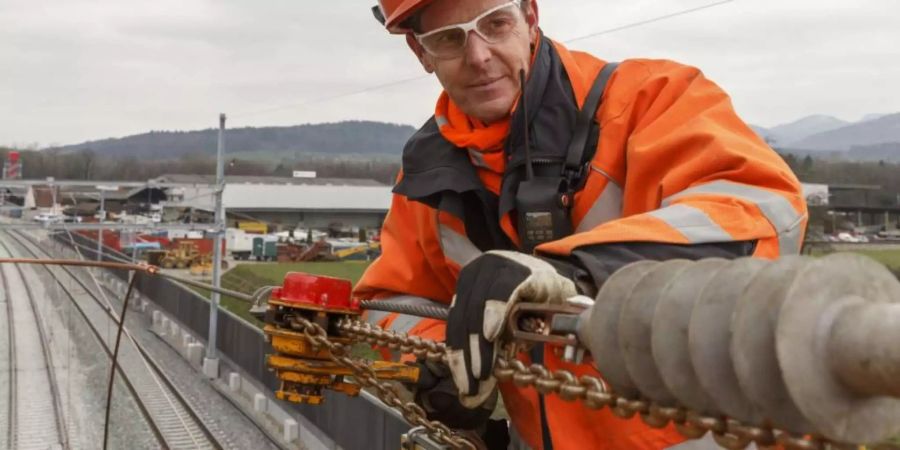 Ein Mitarbeiter der SBB hantiert an einer Fahrleitung.