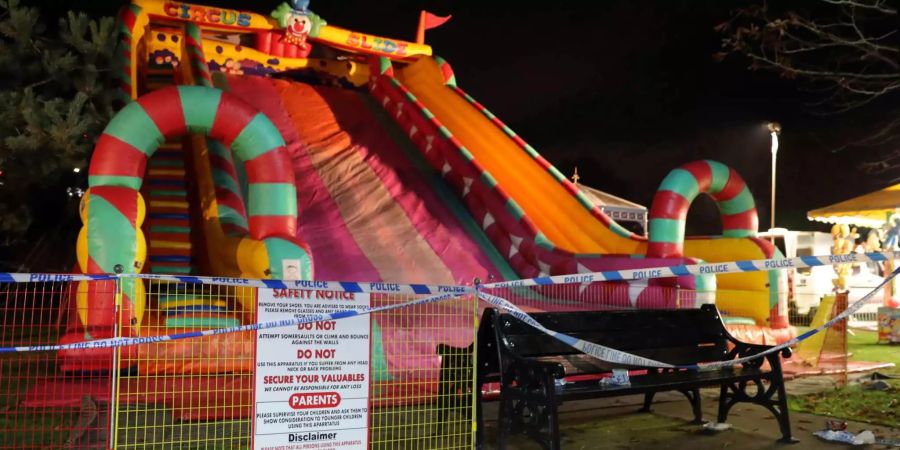 Eine aufblasbare Riesenrutsche steht hinter einer Polizeiabsperrung auf einer Chilbi. Der Festplatz in der Nähe von London wurde nach einem Unfall auf der Rutsche, bei dem mehrere Kinder verletzt wurden, am Samstagabend umgehend evakuiert, wie ein Sprecher der Polizei in Surrey mitteilte. Die Opfer hätten vermutlich schwere Verletzungen erlitten.