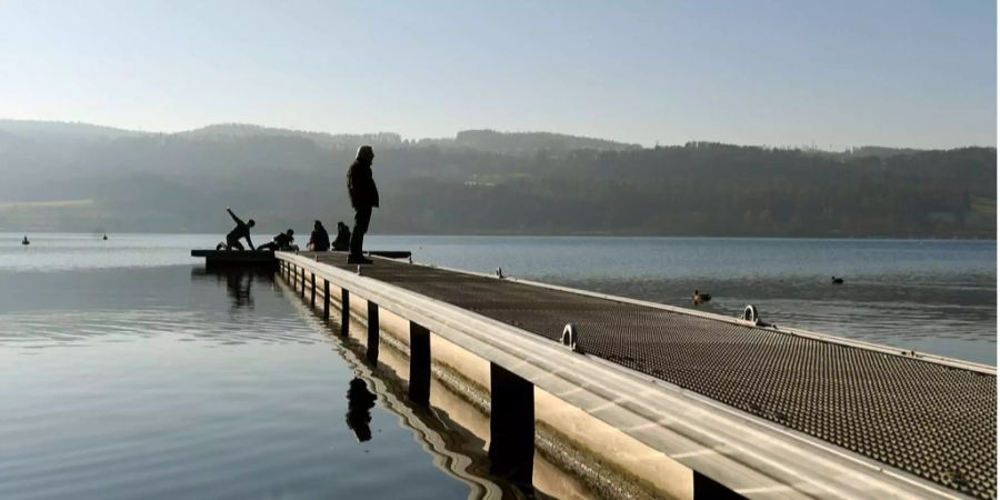 Menschen geniessen an einem Wintertag die Sonne auf dem Greifensee in Zürich.