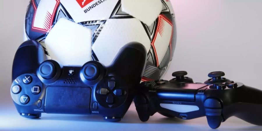 Zwei PlayStation-Controller liegen neben einem Fussball.