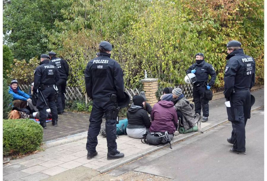 Aktivisten sitzen in Manheim (D) von Polizisten umringt auf dem Boden.