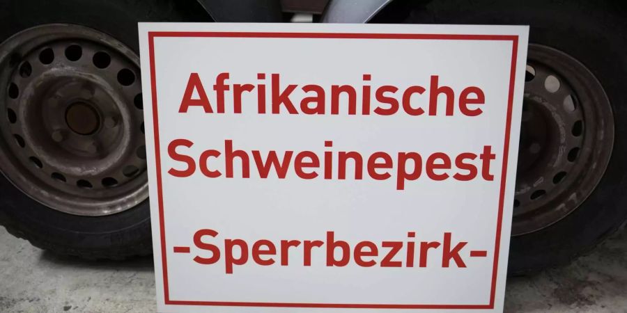 Ein Schild mit der Aufschrift «Afrikanische Schweinepest - Sperrbezirk- » steht bei einem Rundgang durch das hessische Zentrallager für Tierseuchenbekämpfungsmaterial an einen Tieranhänger gelehnt.