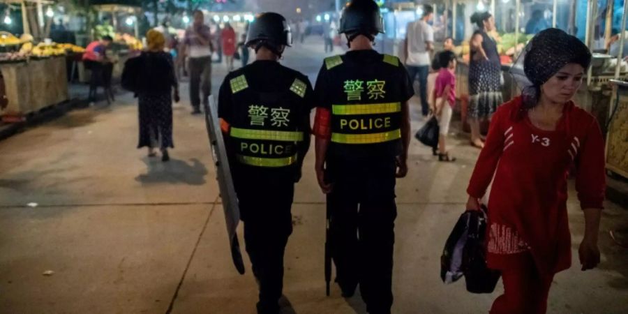 Polizisten patroullieren in einer Stadt in Xinjiang