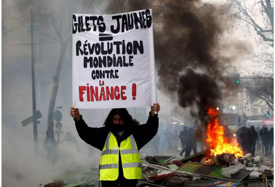 Ein Demonstrant hält ein Schild mit der Aufschrift «Gelbwesten = weltweite Revolution gegen die Finanzwirtschaft».