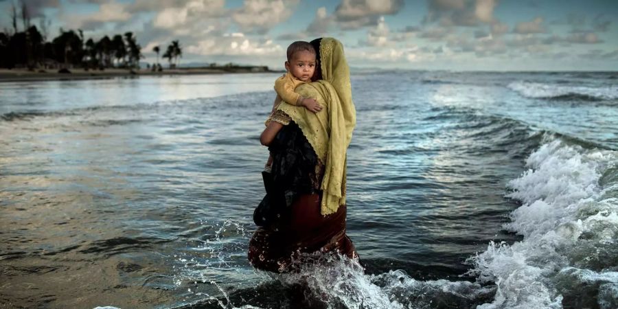 Platz zwei geht an ein Foto des Künstlers K.M. Asad. Es zeigt ein Rohingya-Flüchtling mit ihrem Sohn, nachdem sie auf einem Boot nach Shapuree (Bangladesch) geflüchtet sind.