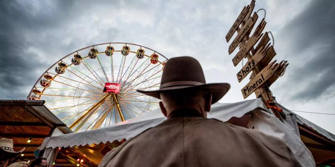 Ein Cowboy blickt am Trucker & Country Festival in Richtung Riesenrad. Trucker & Country Festival