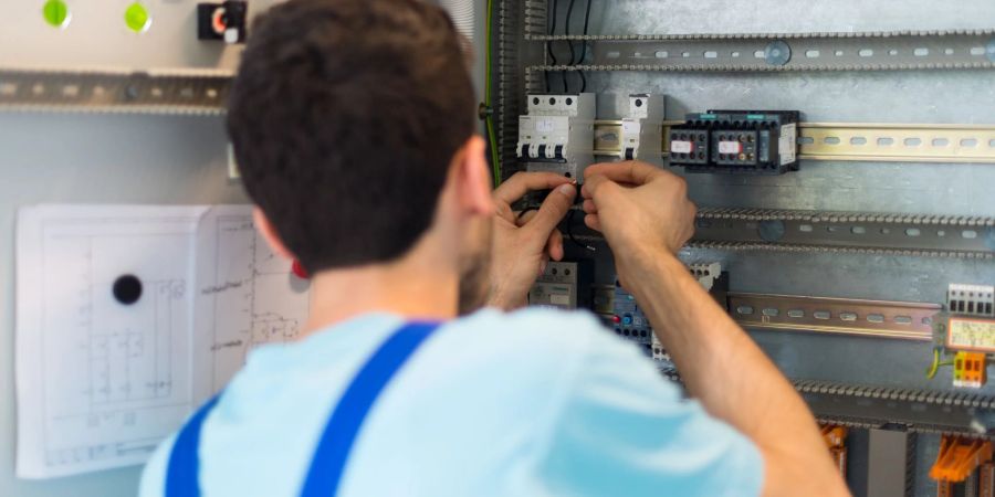 Der 19-jährige Mohammad aus Afghanistan arbeitet im Ausbildungszentrum der Siemens Professional Education an der Verdrahtung eines Schaltschranks.