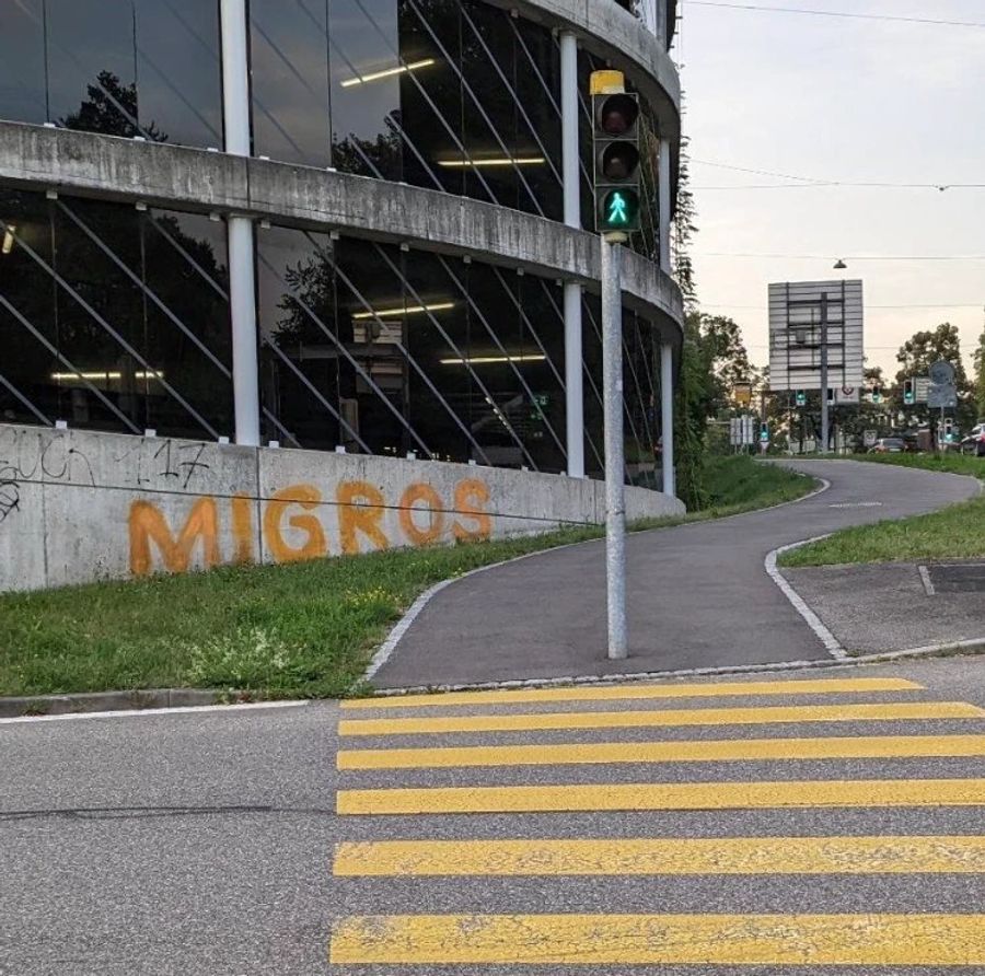 Migros-Logo auf einer Mauer.