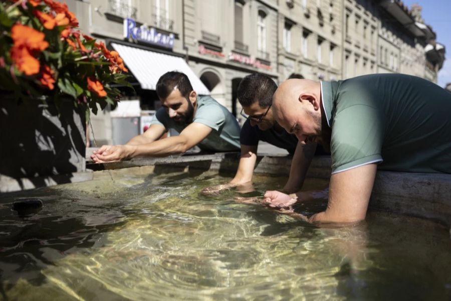 Die Schweiz schwitzt: Hier kühlen sich drei Männer in einem Brunnen in der Berner Altstadt ab.