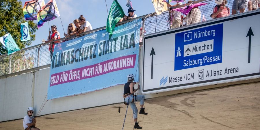 Klimaaktivisten von Extinction Rebellion seilen sich in München von einer Brücke ab.