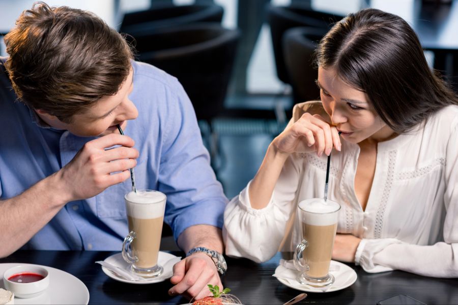 Mann und Frau trinken Milchkaffee und schauen sich verliebt an