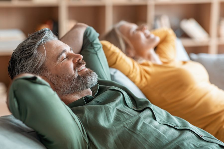Mann und Frau lehnen sich zurück und entspannen sich auf einem Sofa