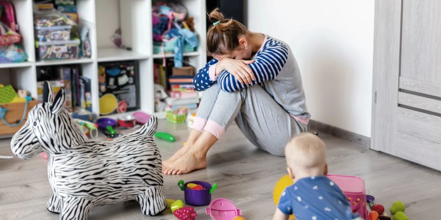 Verzweifelte Mutter mit Baby im Kinderzimmer