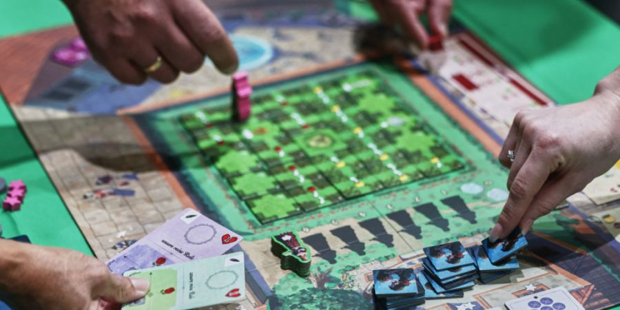 Menschen spielen auf der Publikumsmesse «Spiel Essen» das Brettspiel «Roxane». Foto: Oliver Berg/dpa