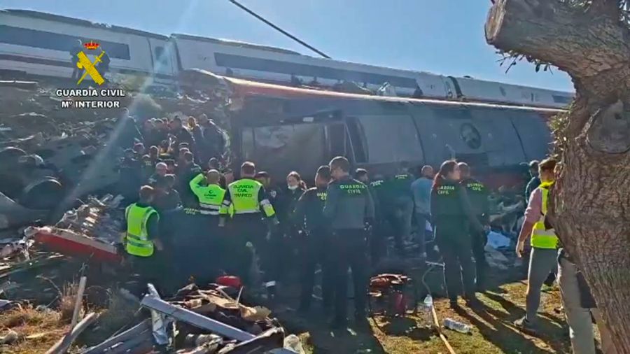 Einsatzkräfte der Guardia Civil und weitere Helfer drängen sich neben einem umgestürzten Waggon.