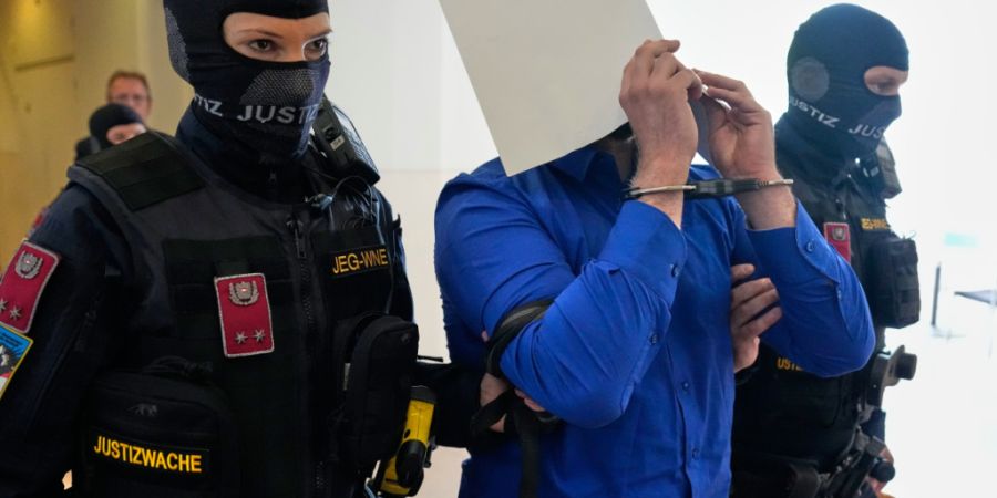 ARCHIV - Der Angeklagte verbirgt sein Gesicht hinter Aktenordnern, als er aus dem Gerichtssaal geführt wird. Foto: Matthias Schrader/AP/dpa