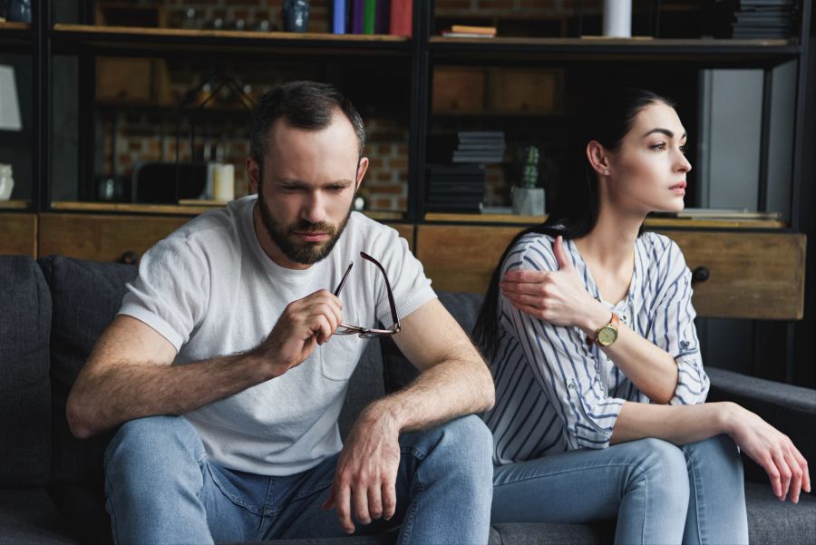 paar schaut voneinander weg, im wohnzimmer sitzend